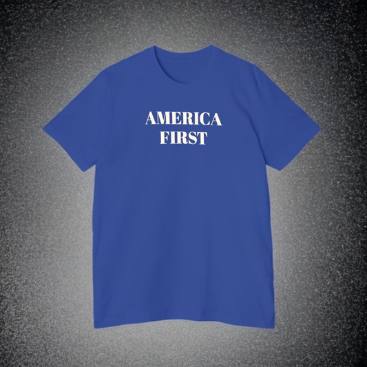 Blue t-shirt with 'America First' printed in bold white letters on the front, displayed against a textured gray background.