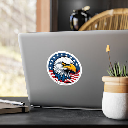 Round patriotic sticker featuring a bold illustration of a bald eagle with a sharp, determined expression. The eagle is set against a background of stars and stripes, symbolizing the American flag displayed on the back of a laptop