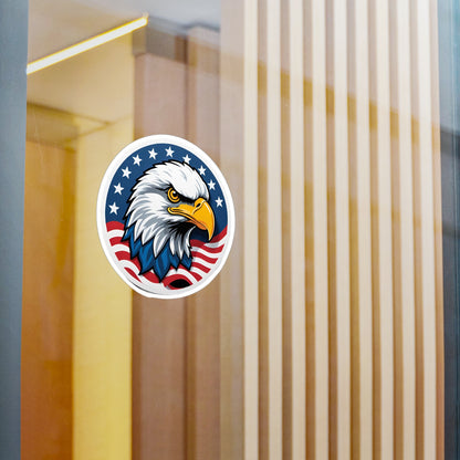 Round patriotic sticker featuring a bold illustration of a bald eagle with a sharp, determined expression. The eagle is set against a background of stars and stripes, symbolizing the American flag displayed on a window