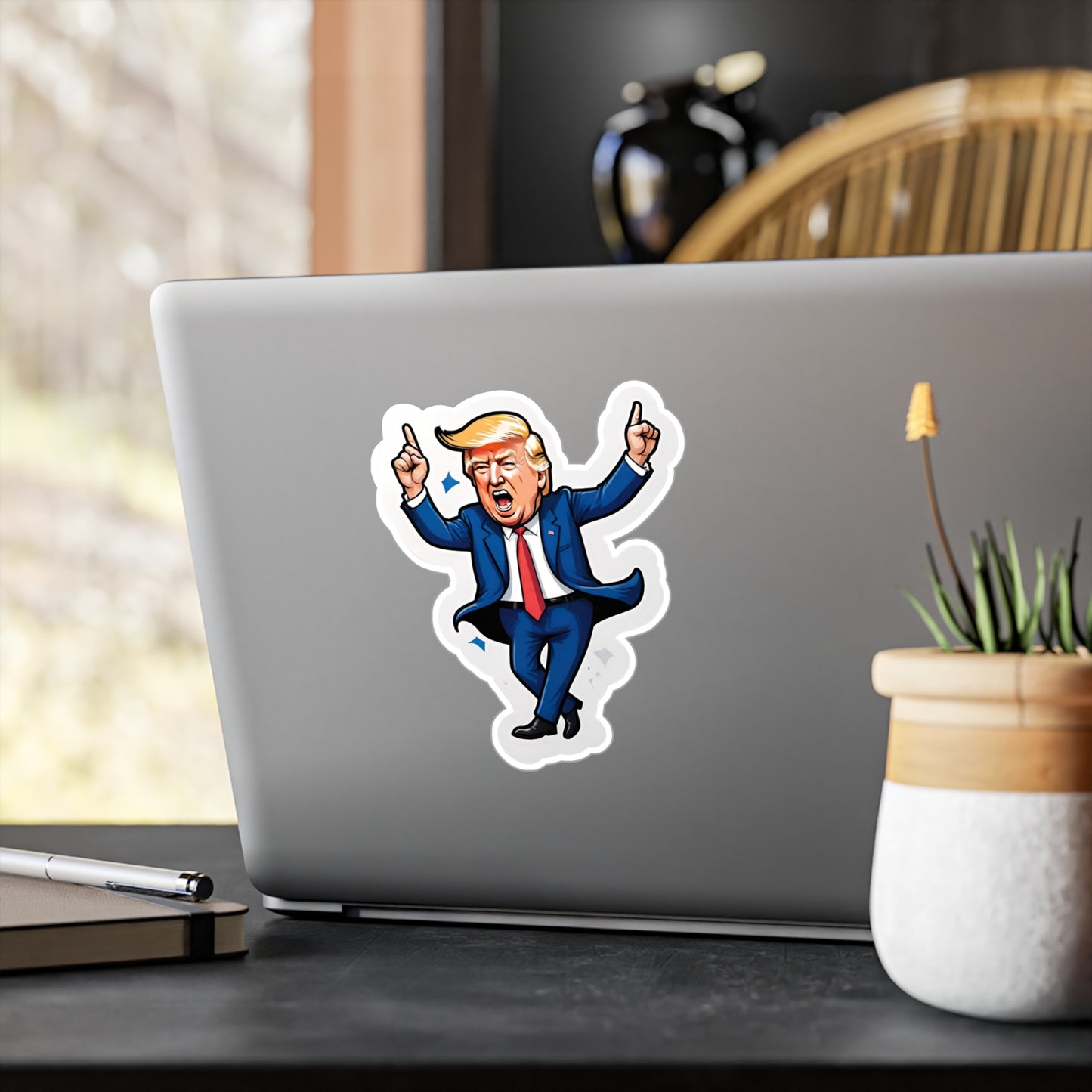 Vinyl car decal of a cartoon looking Donald Trump, dancing with his hands in the air displayed on the back of a laptop