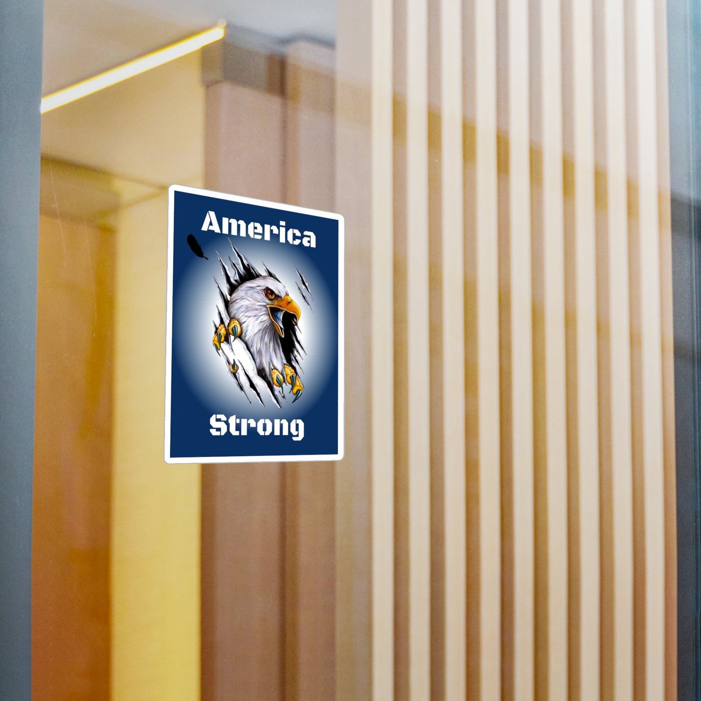 Blue decal showing an eagle ripping through the middle of the design with the words, "America Strong", around the eagle being displayed on a window.